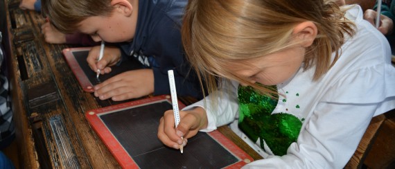 zwei Kinder schreiben über zwei Schultafeln gebeugt
