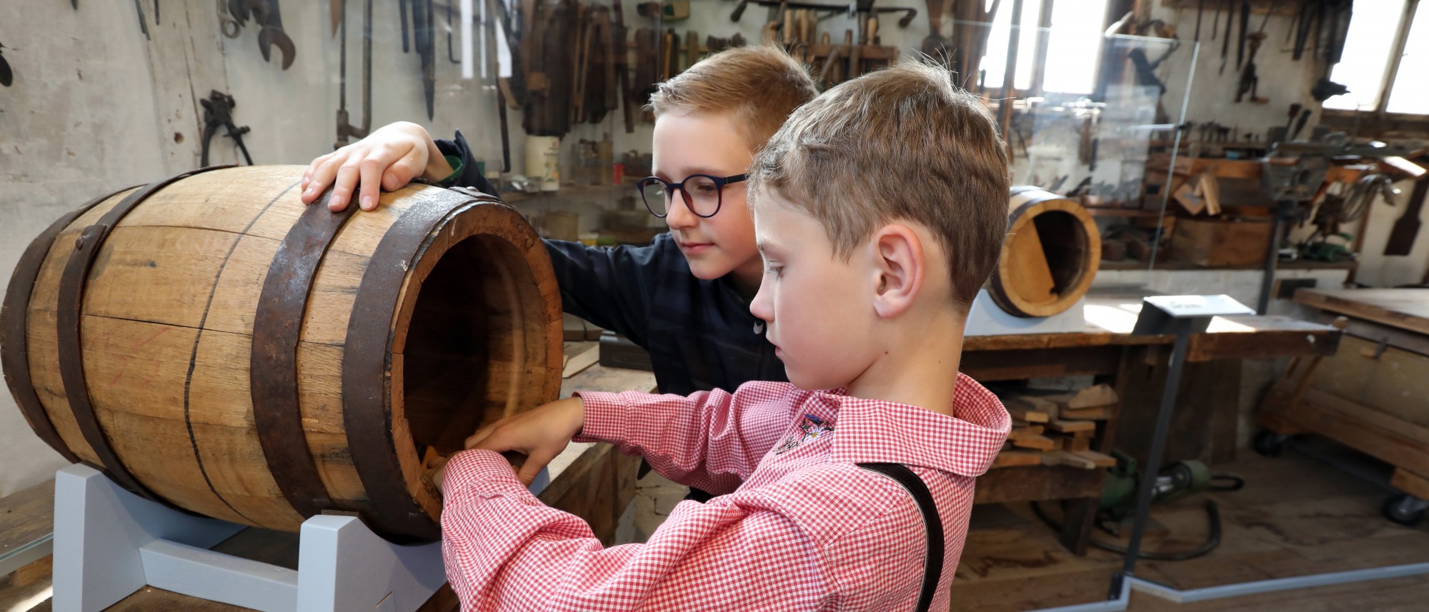 Zwei Kinder betasten ein kleines Holzfass