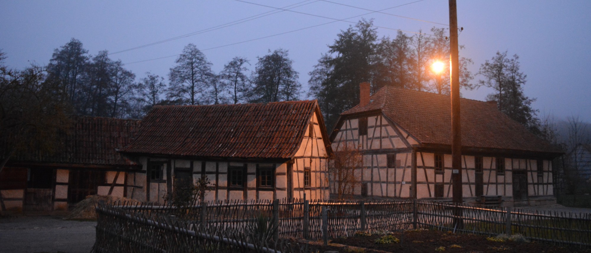 historische Straßenbeleuchtung in der Dämmerung vor zwei Fachwerkhäusern