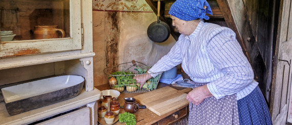 Frau in historischer Kleidung bereitet Essen in einer K&uuml;che zu