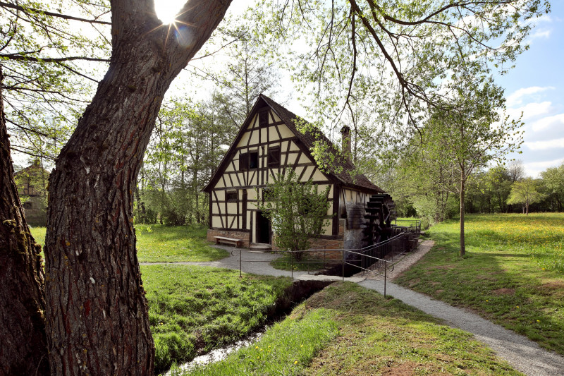 Wasserm&uuml;hle im Fachwerkstil inmitten einer gr&uuml;nen Wiese und B&auml;umen