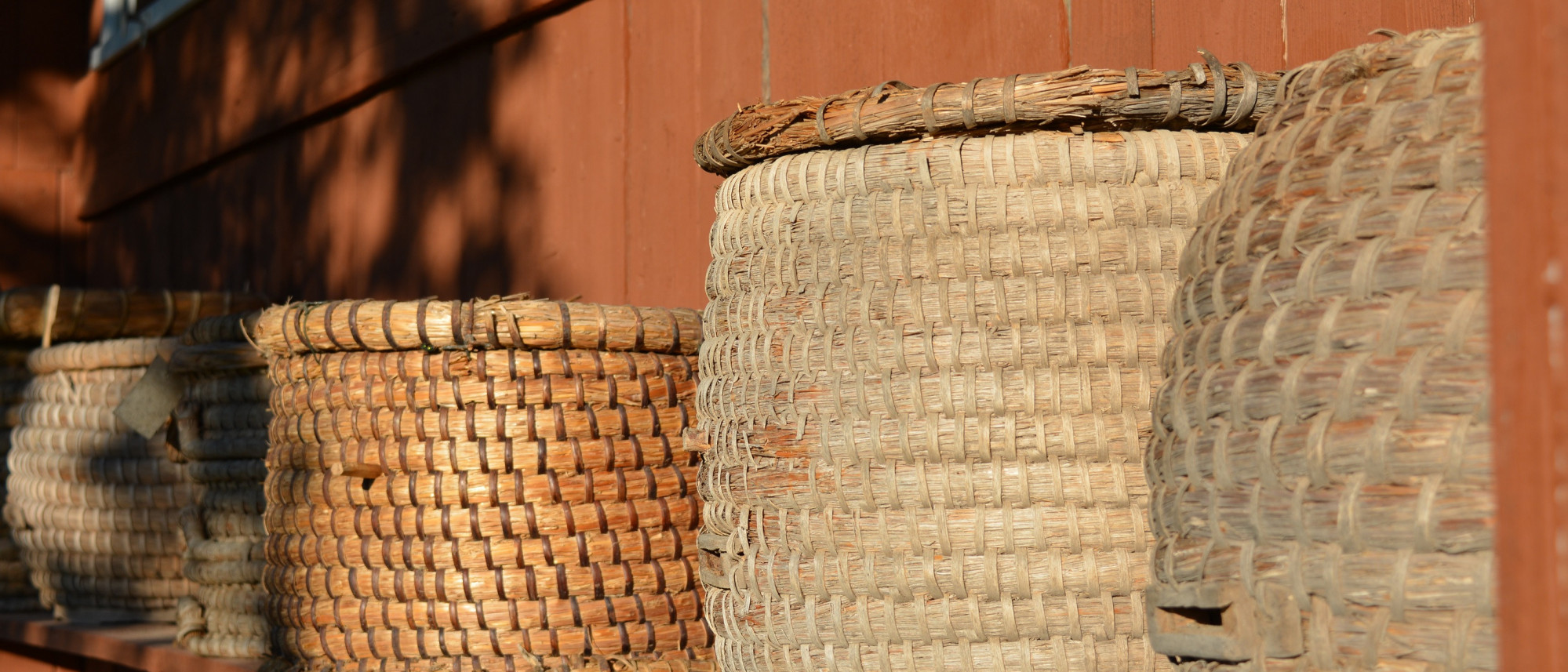 vier Bienenk&ouml;rbe vor rotgestrichener Holzwand
