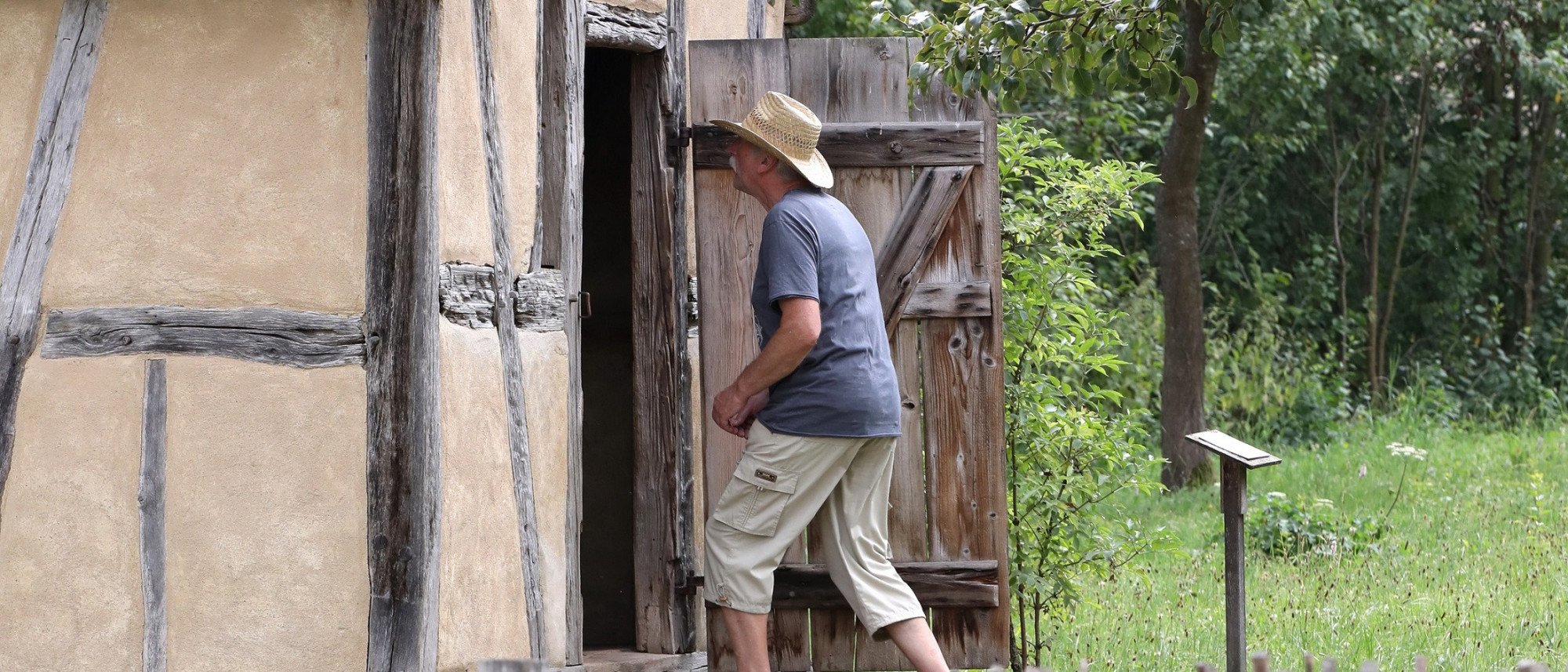 Mann in Freizeitkleidung betritt ein kleines Fachwerkgebäude