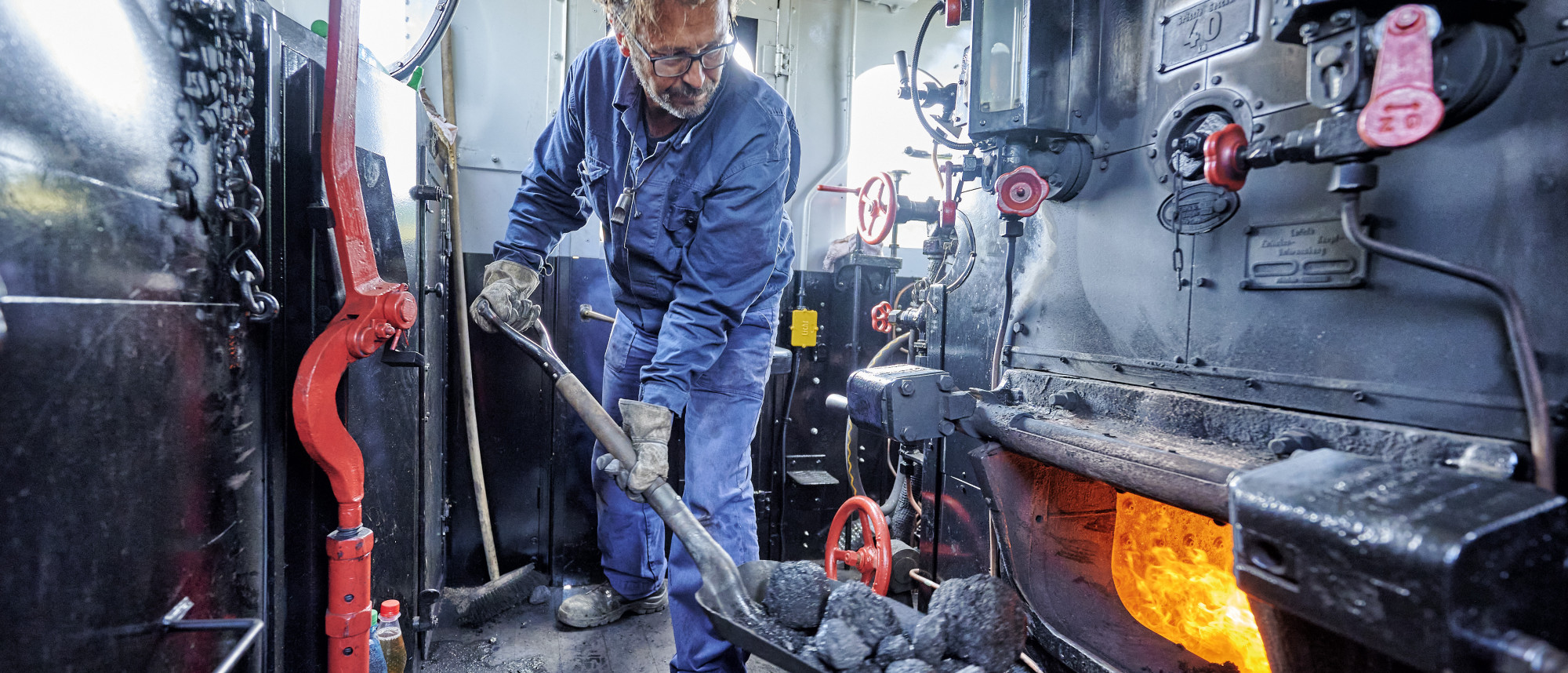 Heizer einer Dampflok bei der Arbeit
