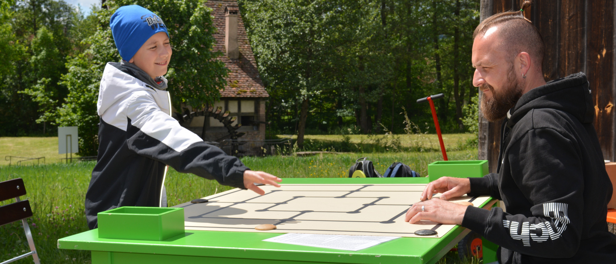 Vater und Sohn spielen eine Partie M&uuml;hle im Freien