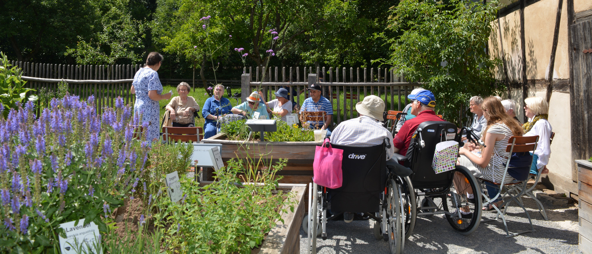 Gruppe sitzt im Kräutergarten