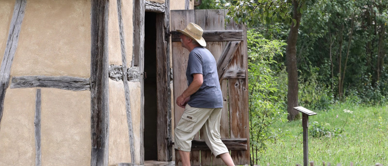 Mann in Freizeitkleidung betritt ein kleines Fachwerkgebäude