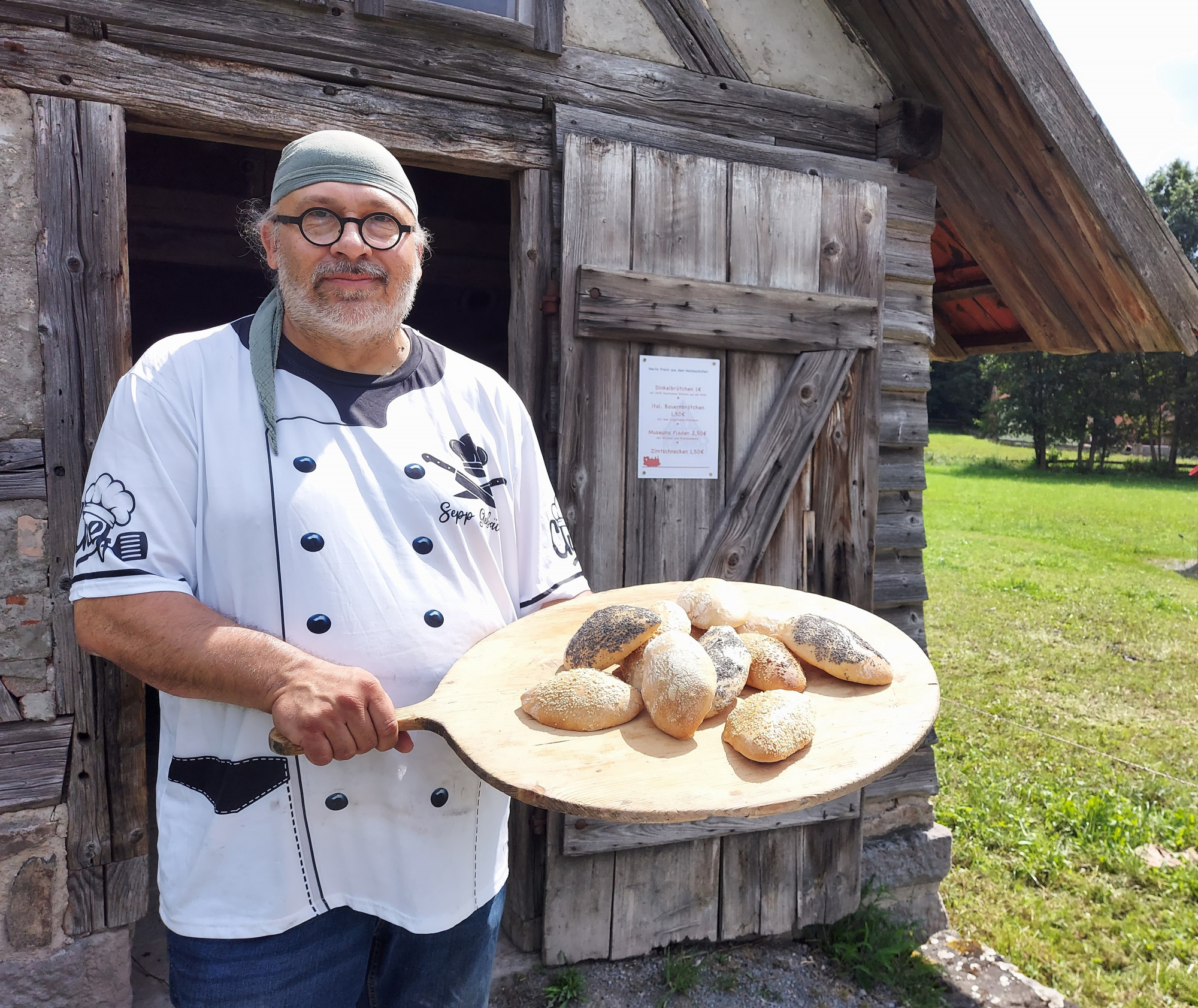 Mann h&auml;lt Holzbrett mit Br&ouml;tchen in der Hand