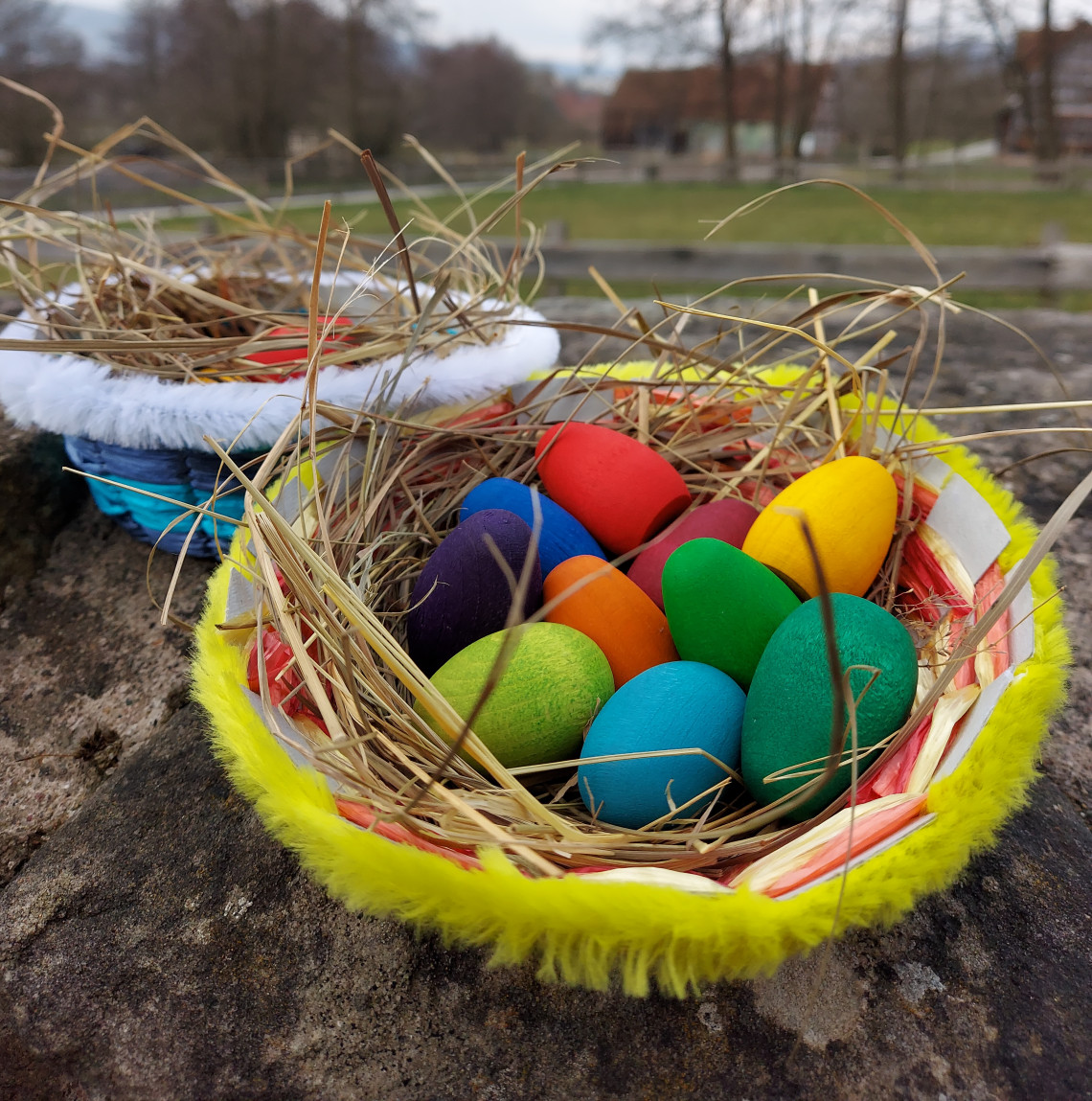 zweu bunt gefüllte Osterkörbchen auf einer Mauer