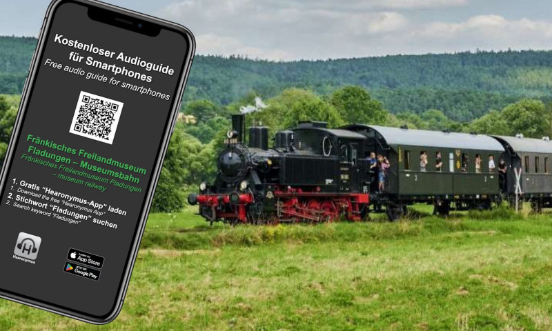 Abbildung eines Smartphones mit Anleitung zum Download Audioguide f&uuml;r Smartphones, im Hintergrund Dampfzug in gr&uuml;ner Landschaft