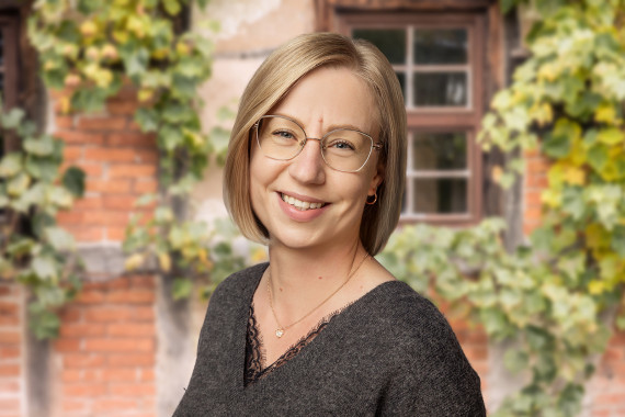 Denise Kirchner, Sammlungsmanagerin vor begr&uuml;nter Hausfassade