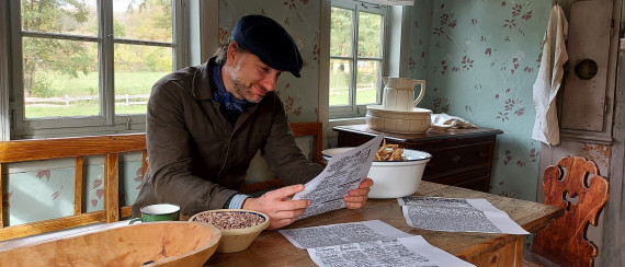 Mann in historischer Kleidung liest Zeitung