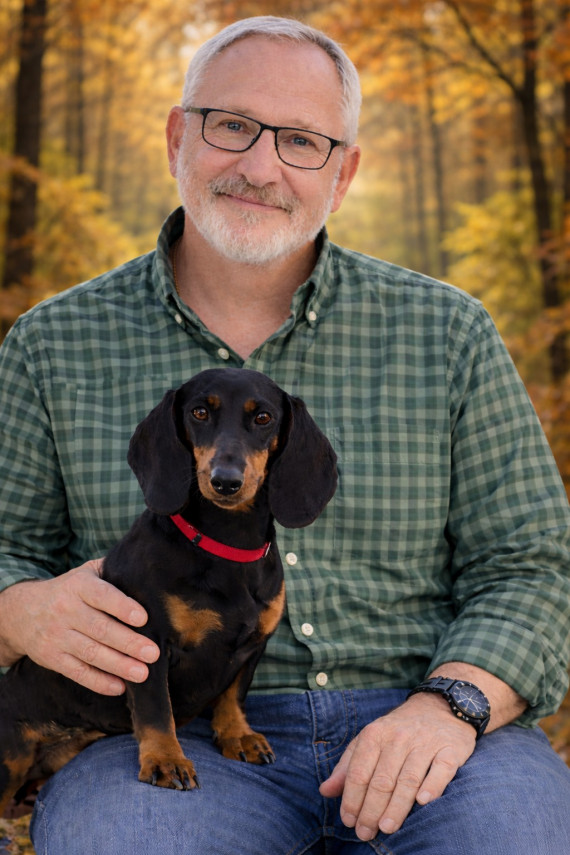 Autor G&uuml;nther H&uuml;th mit Dackel auf dem Schoss, im Hintergrund B&auml;ume mit gelben Bl&auml;ttern