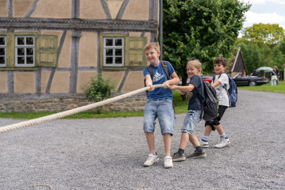 Drei Jungen beim Tauziehen vor Fachwerkgeb&auml;ude