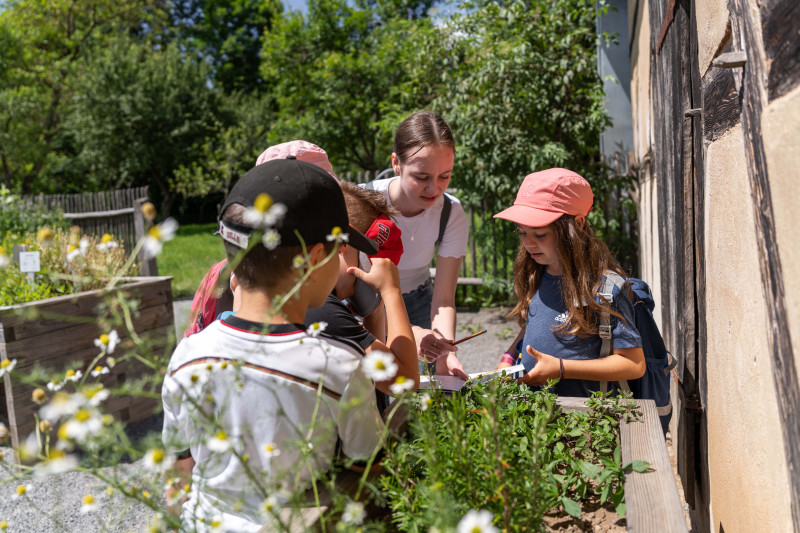 Kinder in einem Garten beim Ausfüllen eines Heftes