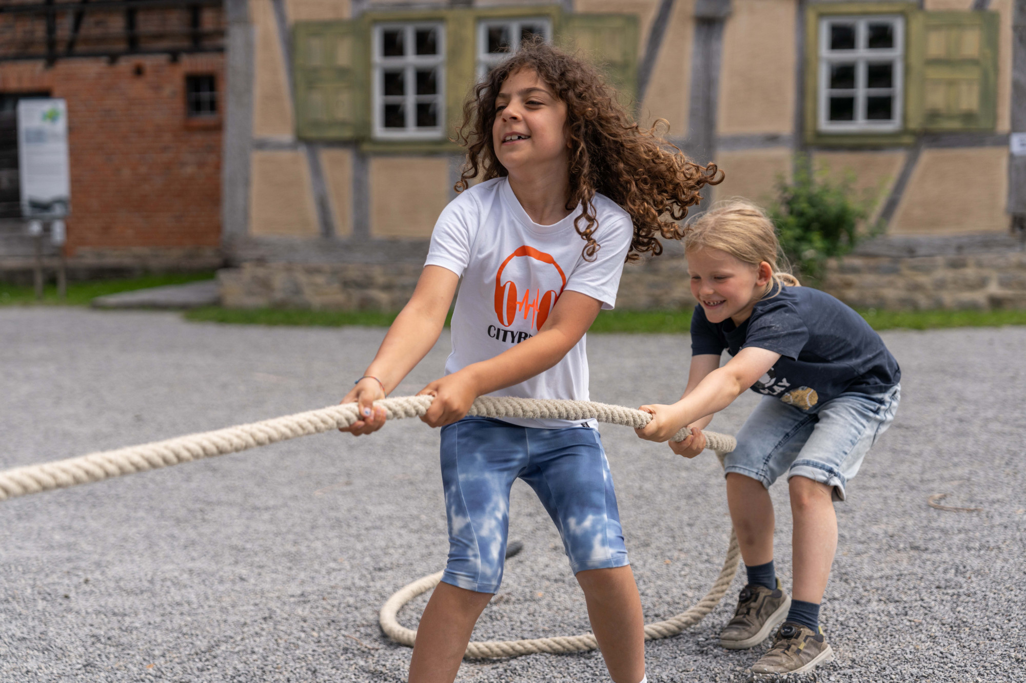 Zwei Kinder beim Tauziehen vor einem Fachwerkgeb&auml;ude