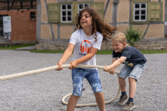 Zwei Kinder beim Tauziehen vor einem Fachwerkgeb&auml;ude